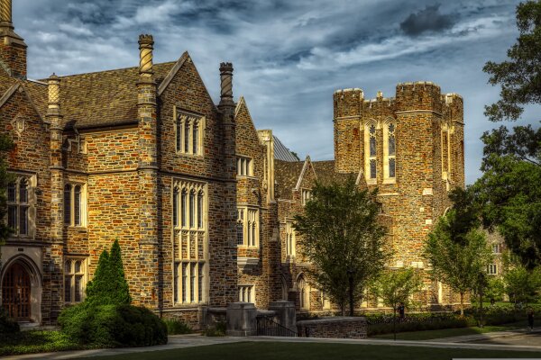 Ein altes Gebäude der Duke University im abendlichen Licht mit grauer Bewölkung.